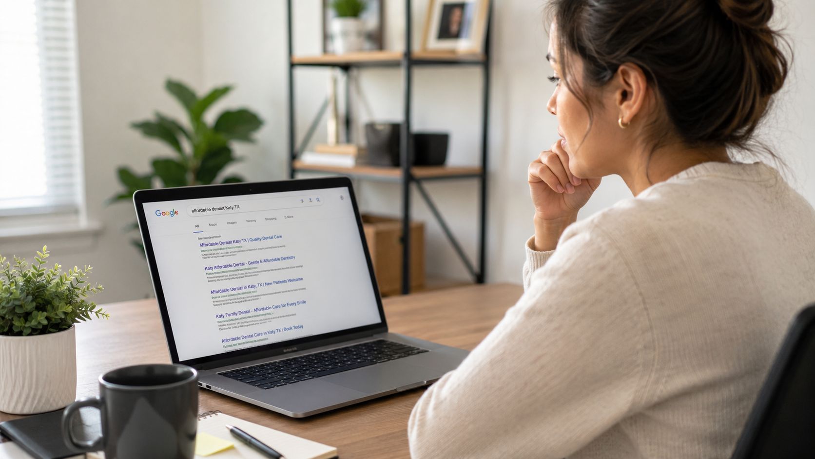 A woman sitting at a desk searching for an affordable dentist in Katy, Texas on her laptop.