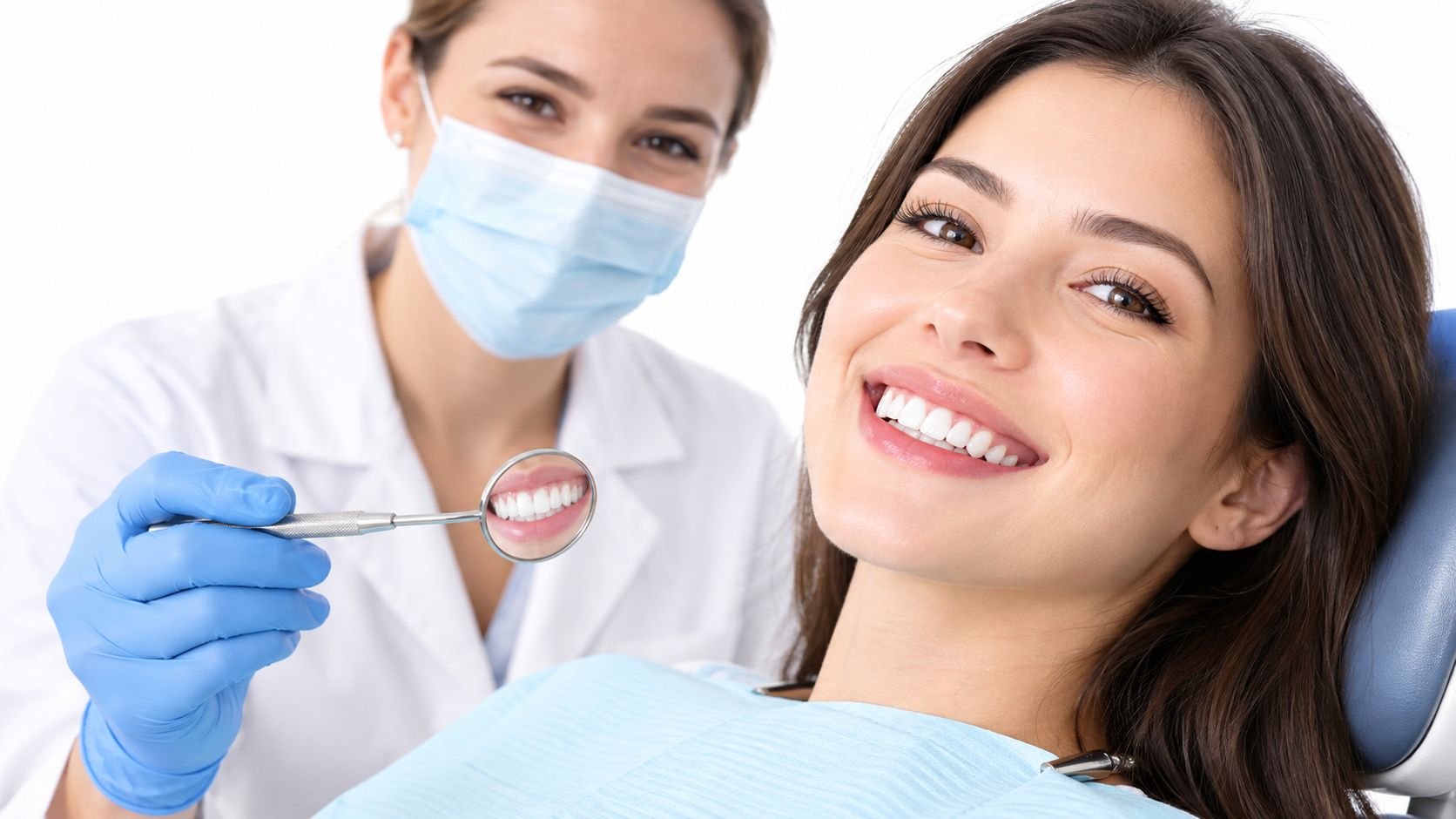 A smiling patient receives a dental exam and cleaning from a professional dentist wearing a mask.