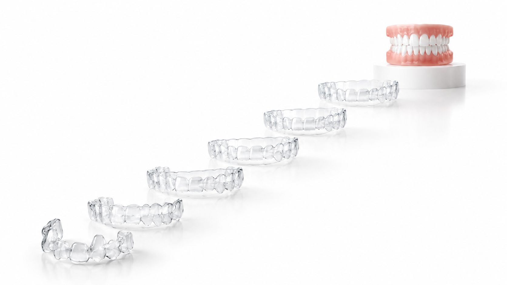 A row of transparent dental aligners leading up to a model of teeth on a white pedestal.